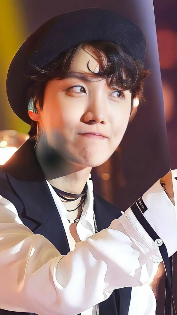 J-hope from BTS, in sunglasses, energetically sings into a microphone during a performance.