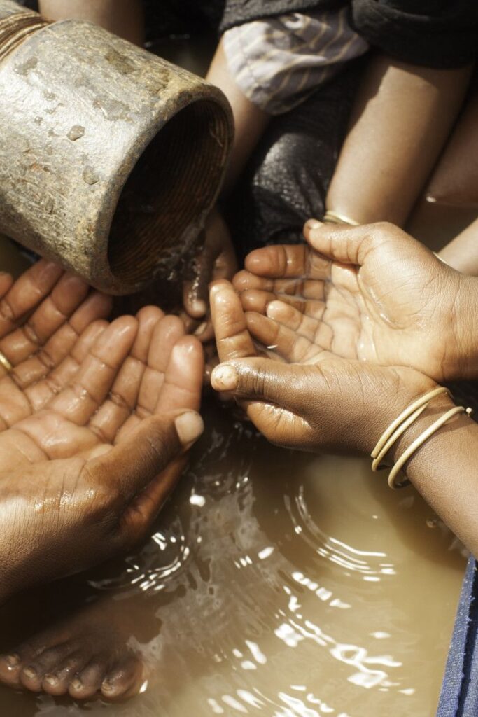 People’s hands in water grasping a bucket, illustrating the urgency of water issues highlighted by India's water strike.